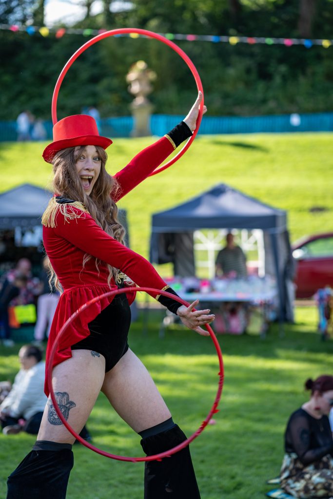 Stilt walker with hulahoops performing at LancsFest24 in a showgirl costume